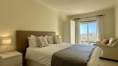 a bedroom with a bed with a window and a chair at Wave by Check-in Portugal in Albufeira