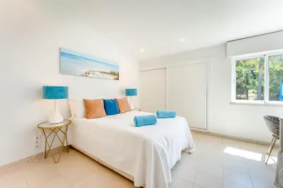 a white bedroom with a bed and a window at Casa Aurora in Vale do Lobo