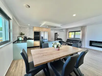 a kitchen and living room with a wooden table and chairs at Villa 20age - Jacuzzi - Heated pool - Algarve in Albufeira