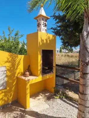 a yellow and white lighthouse in front of a fence at Casinha da Galé in Galé