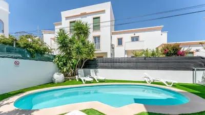 a swimming pool with two chairs and a building at Vivenda Neves in Albufeira by LovelyStay in Vale de Pedras