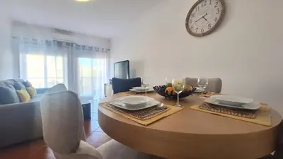 a wooden table in a living room with a clock on the wall at albufeira sweety house in Albufeira