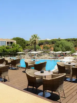 a patio with tables and chairs next to a pool at 3HB Falesia Beach in Albufeira