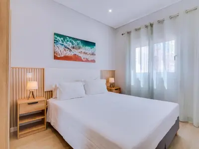 a bedroom with a large white bed and a window at Casa da Avó Marquinhas in Quarteira