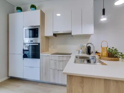 a kitchen with white cabinets and a sink at Casa da Avó Marquinhas in Quarteira