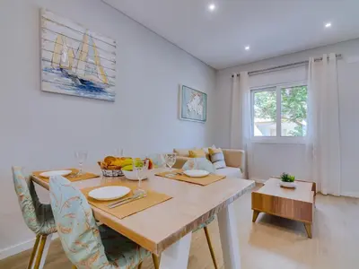 a white dining room with a table and chairs at Casa da Avó Marquinhas in Quarteira