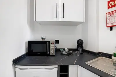 a kitchen with a microwave on a black counter top at Mi Casa Es Su Casa Nº2 in Albufeira