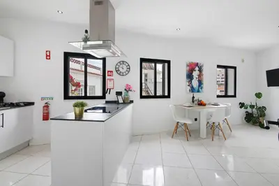 a white kitchen with a counter and a table at Mi Casa Es Su Casa Nº4 in Albufeira