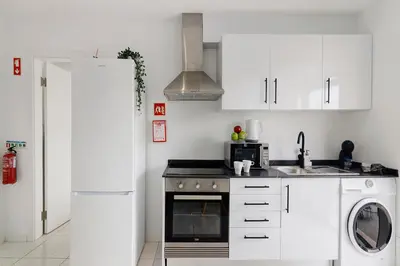 a kitchen with white cabinets and a washer and dryer at Mi Casa Es Su Casa Nº5 in Albufeira