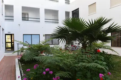 a white building with windows and plants in front of it at Cartaia Apartamento Leste in Quarteira