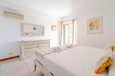 a white bedroom with a large bed and a dresser at Coastal Pines by Seareen in Quarteira