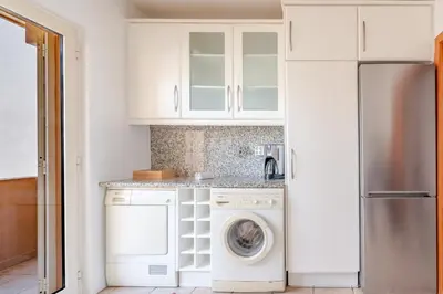 a kitchen with white cabinets and a washer and dryer at Coastal Pines by Seareen in Quarteira