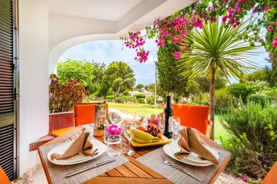 a house with a garden with a palm tree and flowers at Dream House in Clube Albufeira in Albufeira