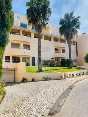 a building with palm trees in front of it at Apartamento T2 duplex - Vilamoura in Quarteira