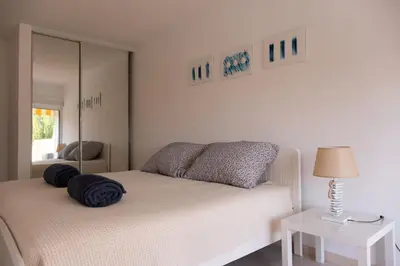 a white bedroom with a bed and a mirror at Apartamento T2 duplex - Vilamoura in Quarteira