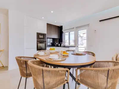 a kitchen and dining room with a wooden table and chairs at T2 Moderno e Renovado a 500m da praia de Quarteira in Quarteira