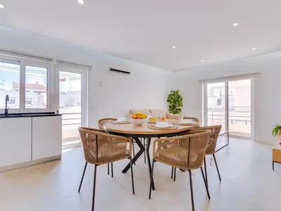 a kitchen and dining room with a table and chairs at T2 Moderno e Renovado a 500m da praia de Quarteira in Quarteira