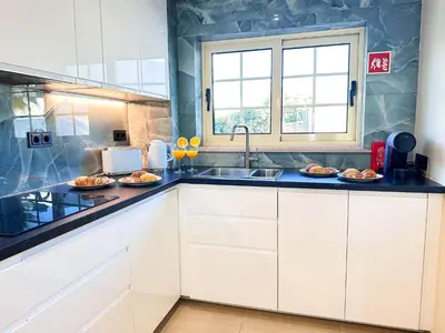 a kitchen with white cabinets and a sink at Oura Modern Poolside Condo by BeCherish in Vale de Pedras
