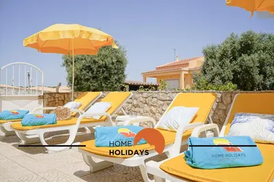 a row of yellow lounge chairs and an umbrella at #240 Beach House - Casa da Balaia by Home Holidays in Olhos de Água