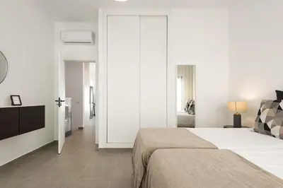 a white bedroom with a bed and a tv at Castilhos 2 - City center by HD in Faro