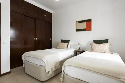 a bedroom with two beds and a brown cabinet at Salty - Near the city by HD in Faro