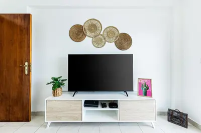 a living room with a flat screen tv on a white wall at O Canto do Oceano T2 Albufeira in Albufeira