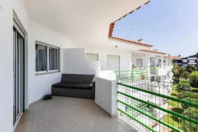 a balcony with a black bench on a white house at O Canto do Oceano T2 Albufeira in Albufeira