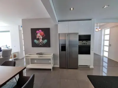 a kitchen with a stainless steel refrigerator and a table at Luxury Design Villa (Private Pool & Jacuzzi) in Albufeira