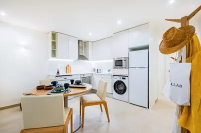 a kitchen with white cabinets and a table and chairs at Apartamento oceano in Albufeira