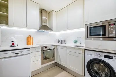 a kitchen with white cabinets and a washer and dryer at Apartamento oceano in Albufeira
