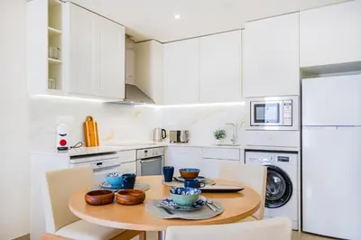 a kitchen with a wooden table and white cabinets at Apartamento oceano in Albufeira