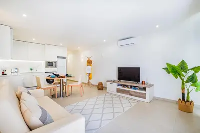 a living room with a white couch and a kitchen at Apartamento oceano in Albufeira