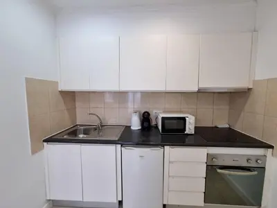 a kitchen with white cabinets and a sink and a microwave at By the Sea Apartments B3 in Albufeira