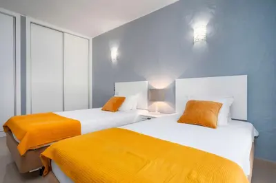 two beds with orange sheets in a room at Balaia Retreat - Nature & Beach in Olhos de Água