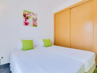 a bedroom with a large white bed with green pillows at Villa Brown's with Private Pool in Vilamoura in Quarteira