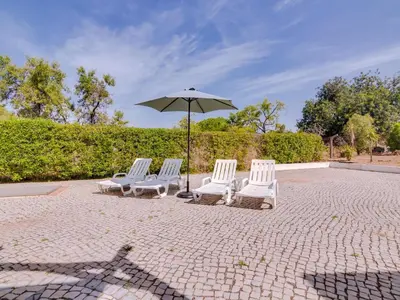 four white chairs and an umbrella on a patio at Villa Brown's with Private Pool in Vilamoura in Quarteira
