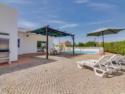 a patio with chairs and umbrellas and a pool at Villa Brown's with Private Pool in Vilamoura in Quarteira