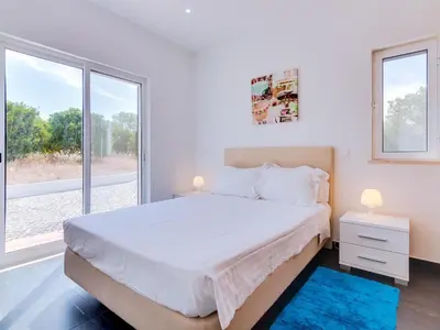 a white bedroom with a large bed and a window at Villa Brown's with Private Pool in Vilamoura in Quarteira