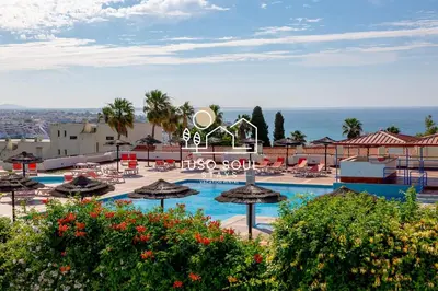 a resort with a swimming pool with umbrellas and the ocean at NEW! Dream Terrace Albufeira Ocean and Pool Views in Bicas