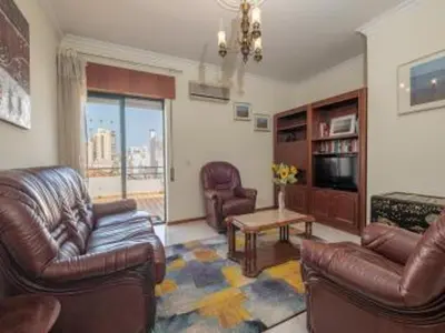a living room with leather couches and a television at Faro Charm Apartment - City Center in Faro