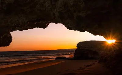 a sunset seen through an opening in a cave on the beach at Charming House in Albufeira with Shared Pool in Albufeira