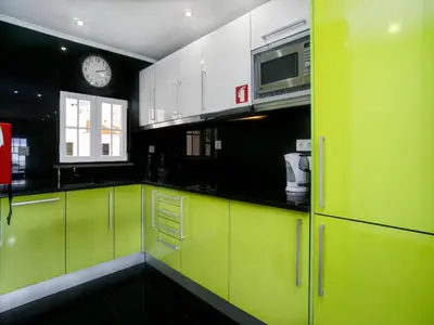 a kitchen with green cabinets and a clock on the wall at Akivillas Albufeira Repose in Albufeira