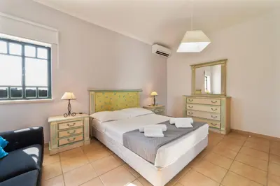 a bedroom with a bed and a chair and a mirror at Tangerine Apartment by HelloVacations in Albufeira