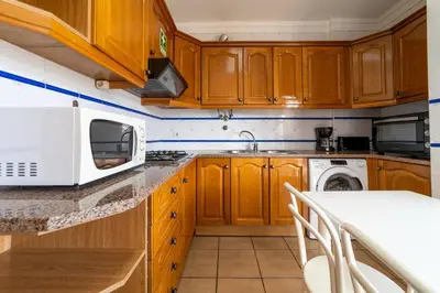 a kitchen with wooden cabinets and a white microwave at Tangerine Apartment by HelloVacations in Albufeira