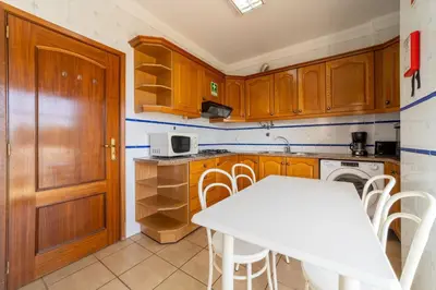 a kitchen with wooden cabinets and a white table at Tangerine Apartment by HelloVacations in Albufeira