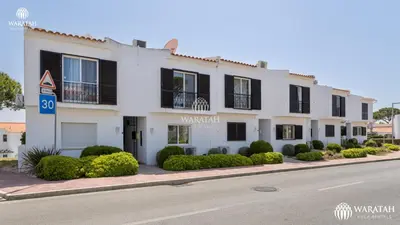 a white building with black shutters on a street at Apartamento Fairway in Loulé