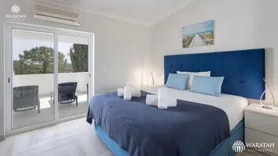 a bedroom with a blue bed and a balcony at Apartamento Fairway in Loulé
