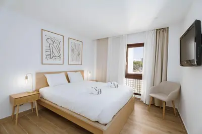a white bedroom with a bed and a tv at Vilamoura Collection in Quarteira