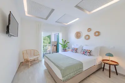 a white bedroom with a bed and a chair at The 23 Suites in Faro