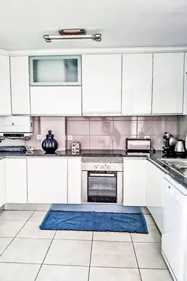 a kitchen with white cabinets and a blue rug at Holiday Home Villa Medusa by Interhome in Vilamoura